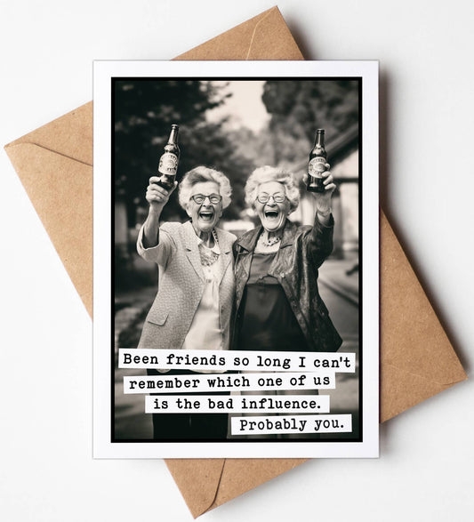 Greeting card with black and white photo of two elderly women holding bottles, text underneath, on a white background with a brown envelope.