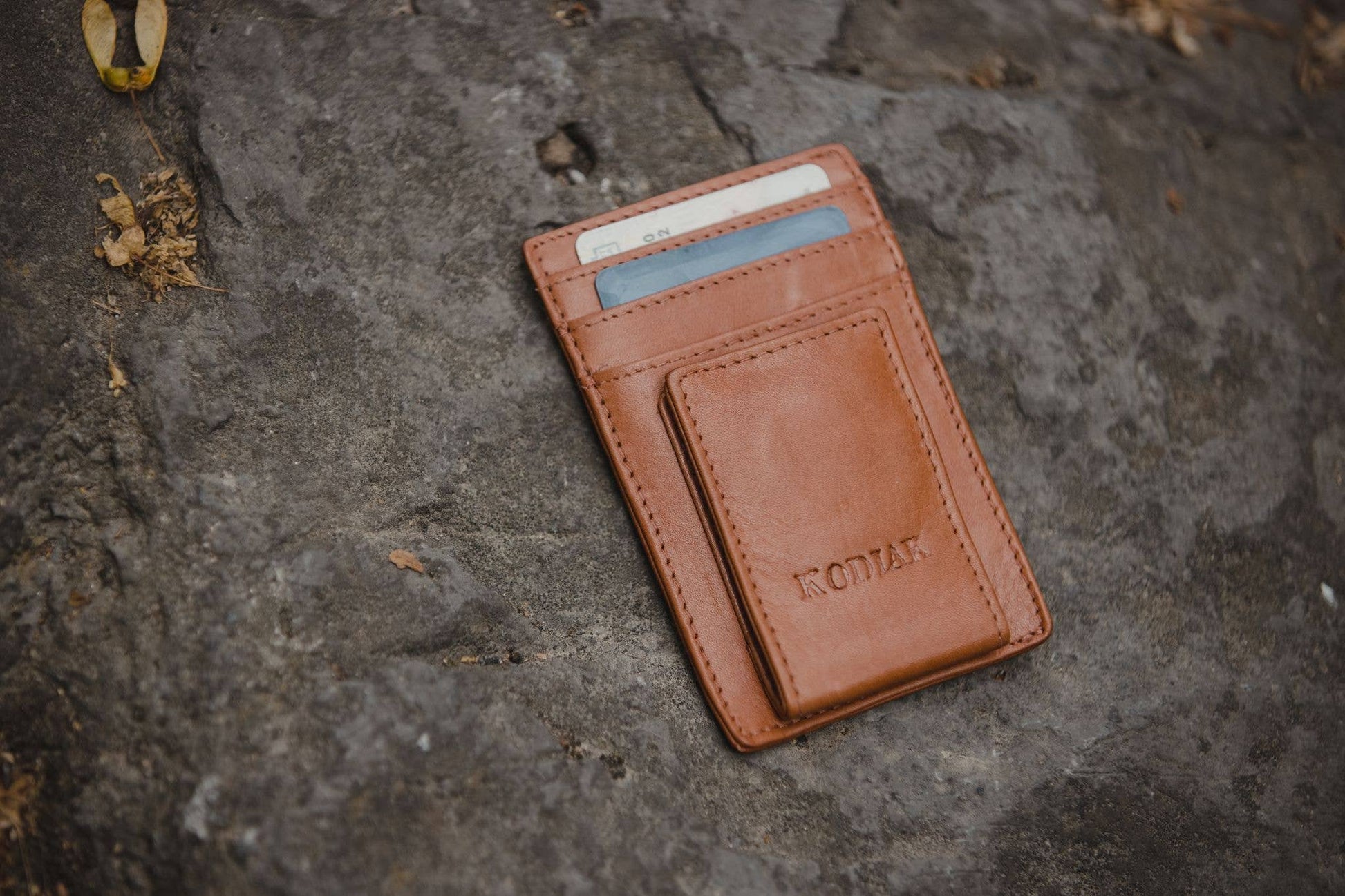 Brown leather wallet with card holder on a textured stone surface