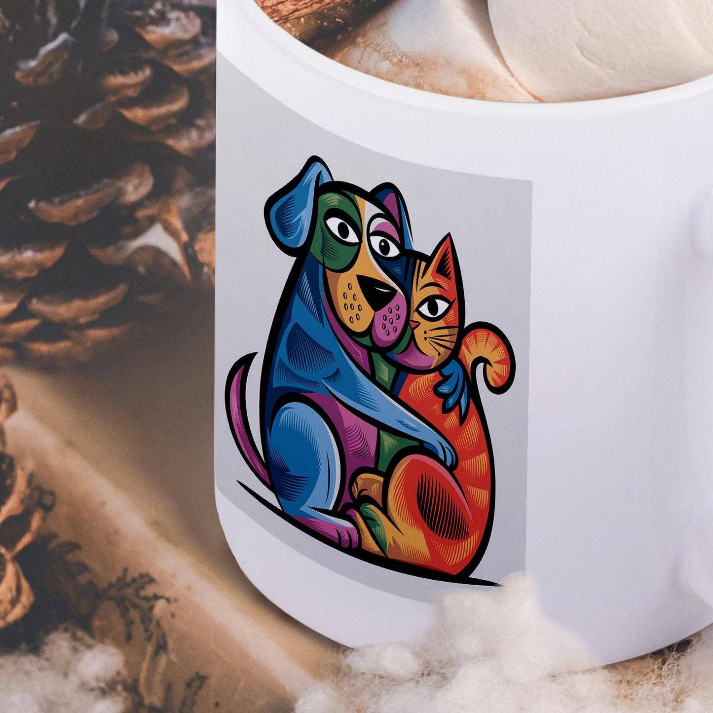 White mug with colorful dog and cat design, filled with hot chocolate and a cinnamon stick, surrounded by pine cones and cotton on a wooden surface.