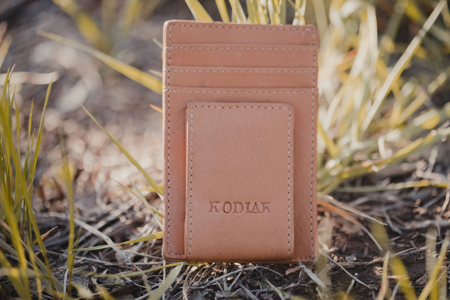 Brown leather wallet with 'Kodiak' branding on grass